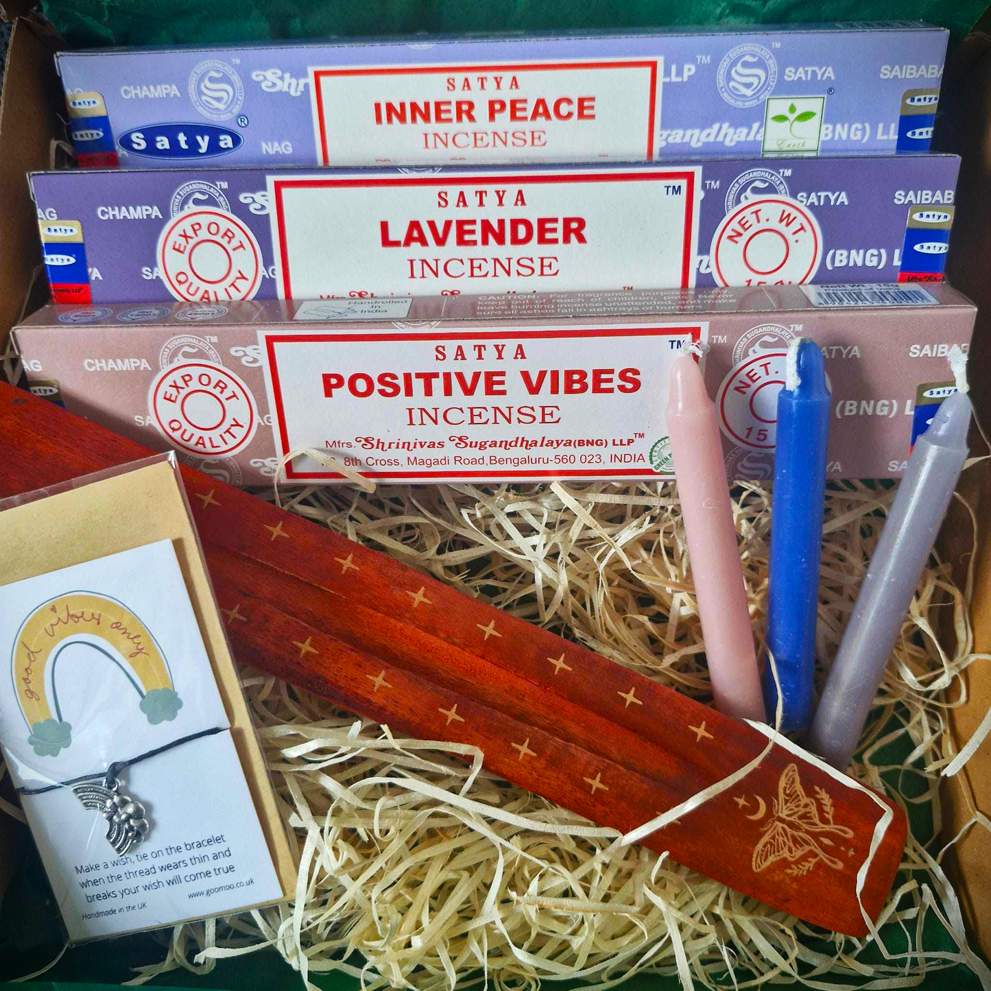 This picture shows the inside of the Positivity Incense Gift Box. Inside, there are 3 incense stick packages. This one contains Inner Peace, Lavender, Positive Vibes. There are 3 spell candles, an ash catcher and a wish Bracelet