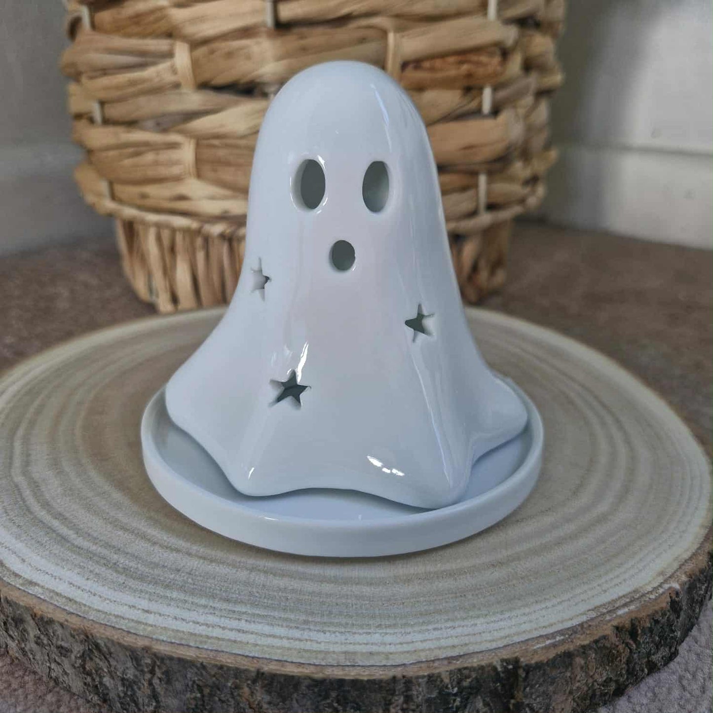 Ghost-shaped candle on a wooden surface with a woven basket in the background