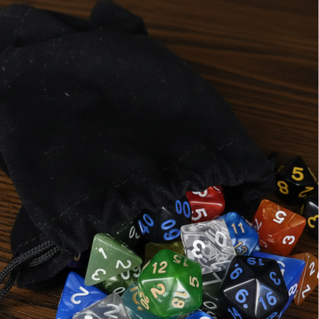 Colorful polyhedral dice spilling out of a black drawstring bag on a yellow surface.