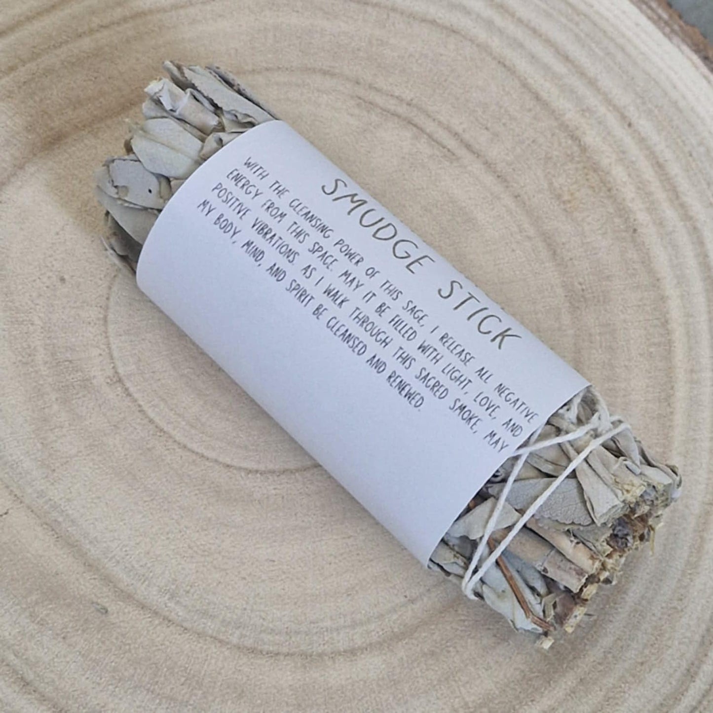 Smudge stick wrapped in paper with text on a wooden surface