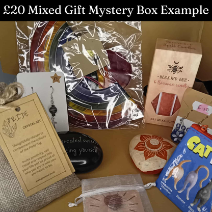Assorted items including crystal sets, candles, and books on a table with text indicating a £20 mixed gift mystery box.