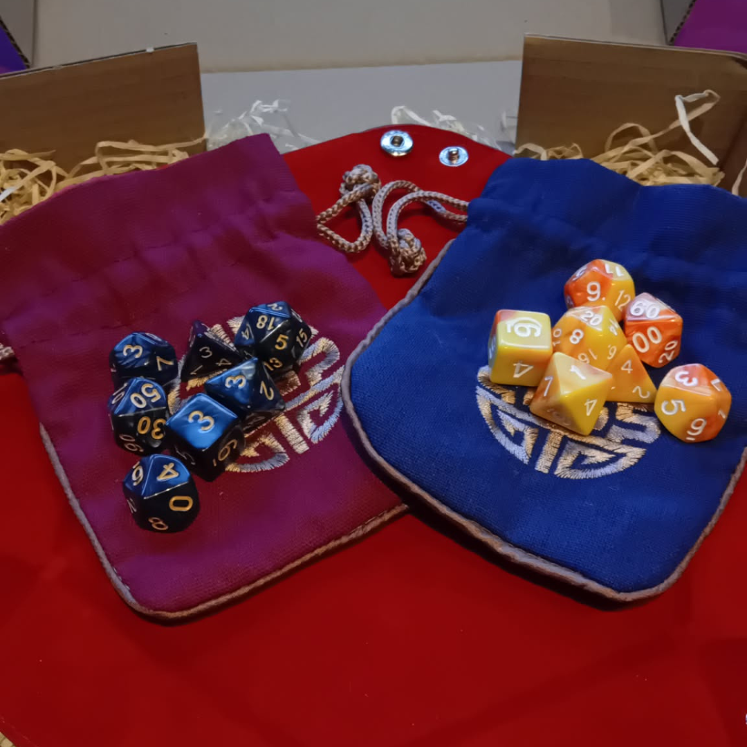 Colorful polyhedral dice on decorative bags with intricate patterns on a dice tray in a Dungeon Master Starter Kit Box