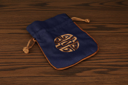 Blue drawstring pouch with gold emblem on a dark oak table