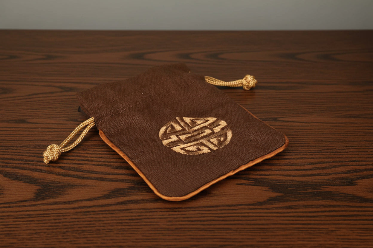 Brown Dungeons and Dragons dice drawstring pouch with a gold emblem on a black surface