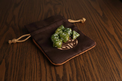 Green dice set in a brown Dungeons and Dragons drawstring dice pouch on a dark surface