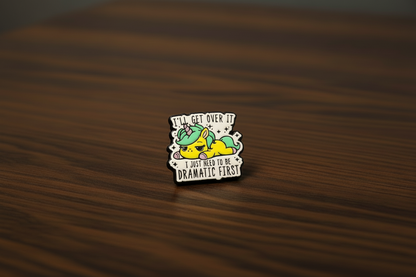 Pin with a cartoon Unicorn on that says I'll get over it, I just need to be Dramatic First on a dark oak table
