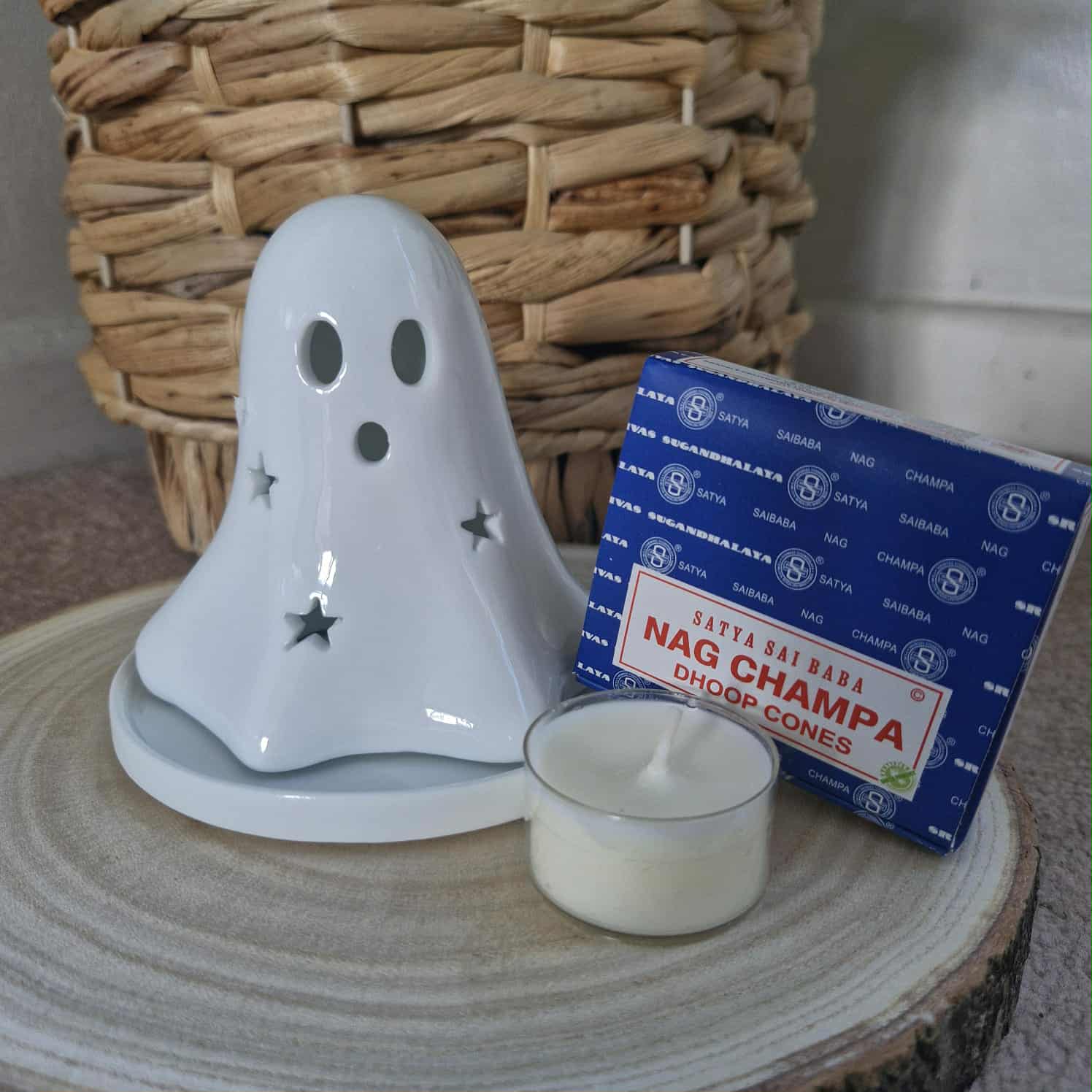 Ghost-shaped candle holder with a box of Nag Champa cones on a wooden surface.
