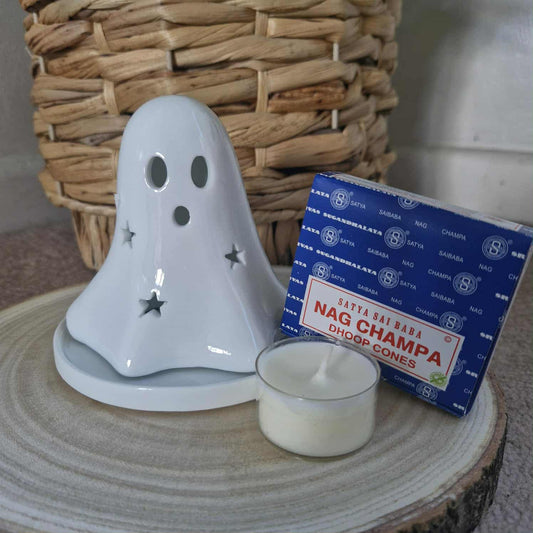 Ghost-shaped candle holder with a box of Nag Champa cones on a wooden surface.