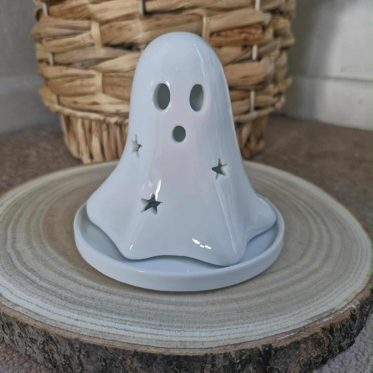 Ghost-shaped candle on a wooden surface with a woven basket in the background