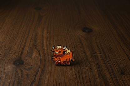 A highland Cow Enamel Pin badge on a dark oak table