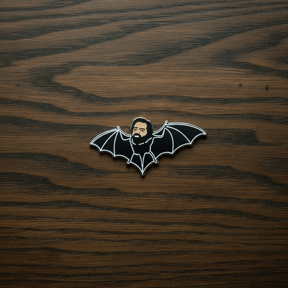 A close up of a Pin Badge of Laszlo on a green Goomoo card with and a black background