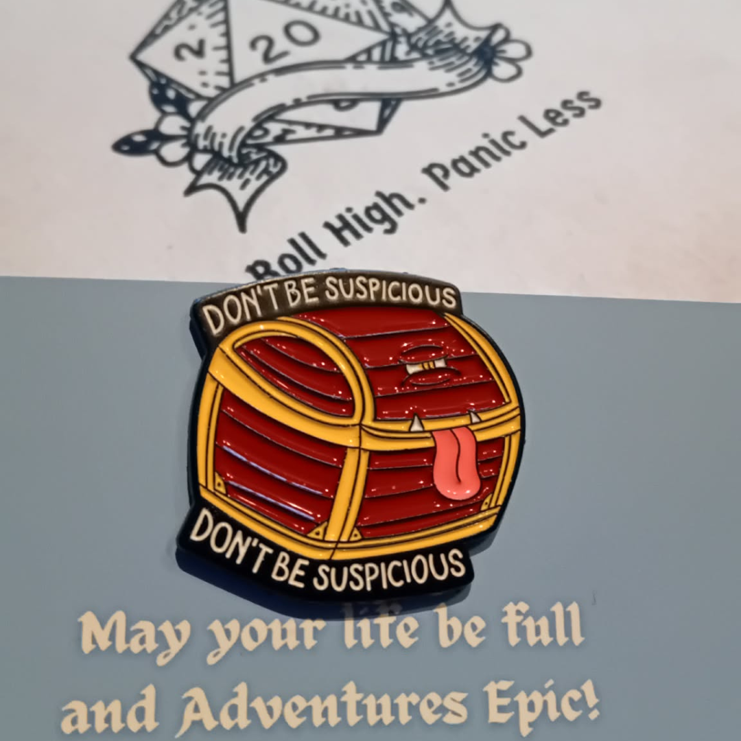 Pin with chest design and text 'Don't be suspicious' on a gray surface with a blurred background.