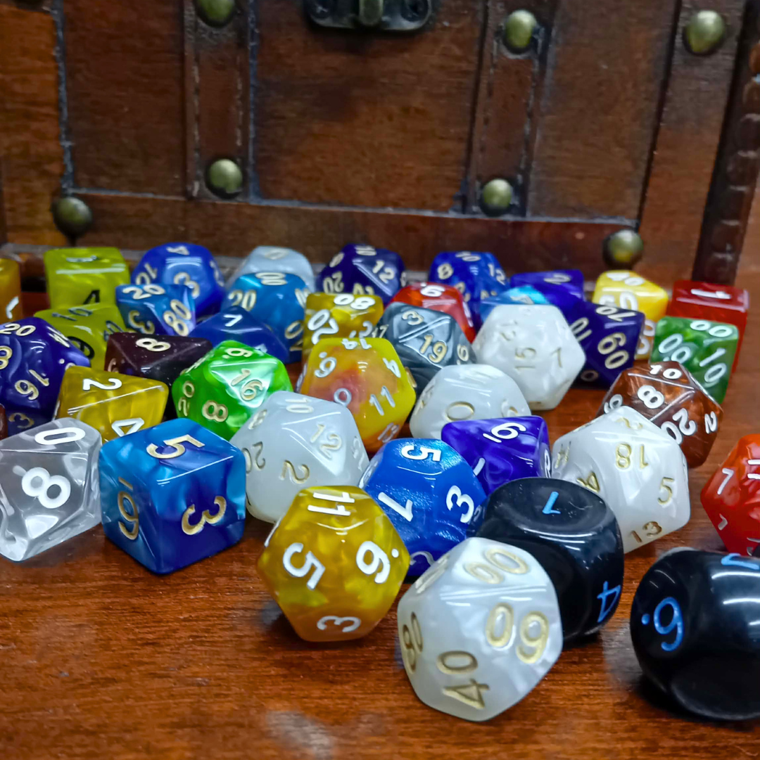Assorted multicolored dice on a wooden surface with a wooden box in the background.