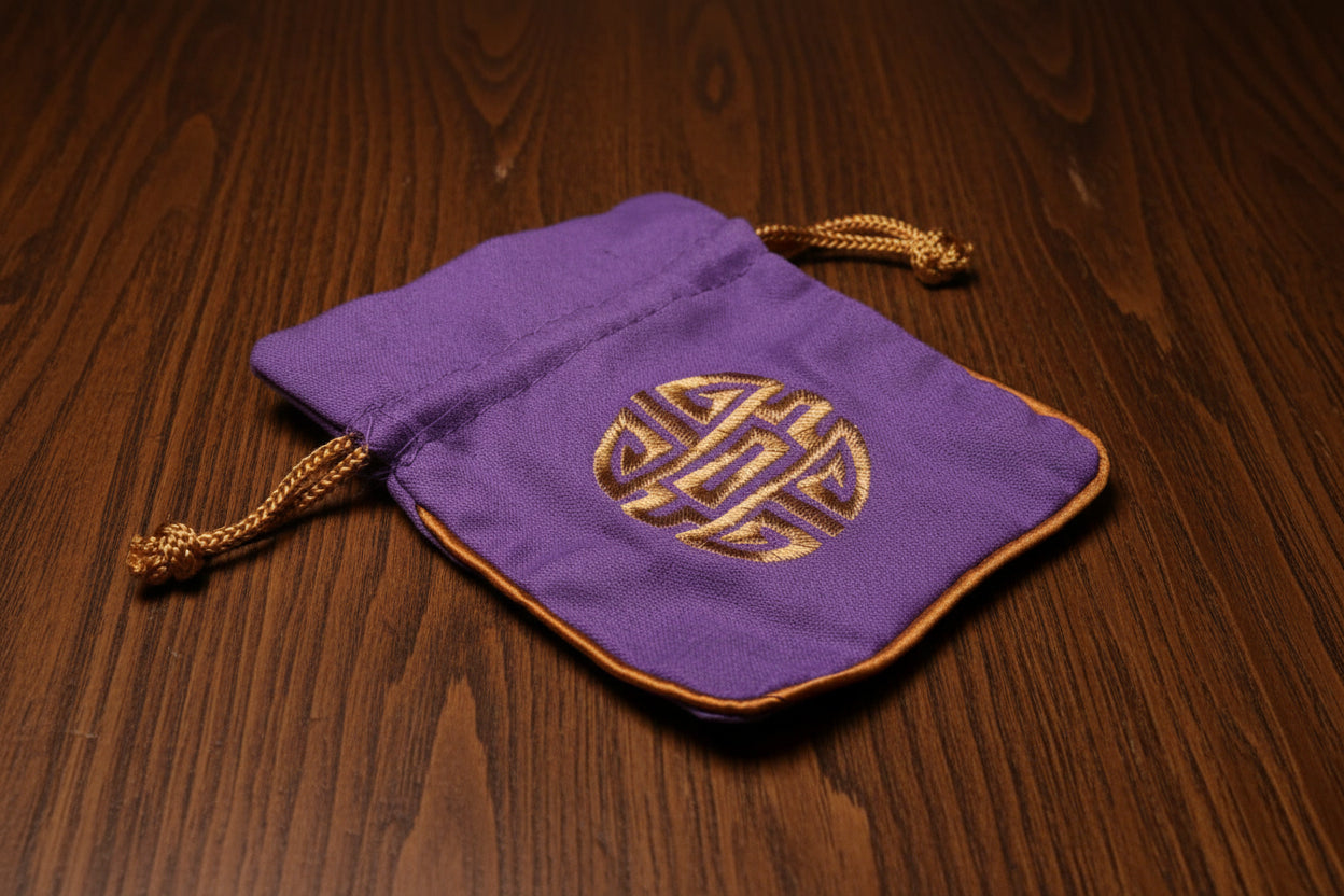 Purple Dungeons and Dragons Dice drawstring bag with gold emblem on a dark oak table