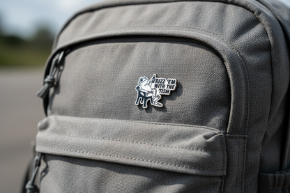 An enamel Pin badge that has a picture of a frog sitting in a chair, holding a bottle saying Rizz 'em with the 'tism on a backpack