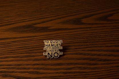 An enamel Pin badge that says, to quote Hamlet Act III, Scene III, Line 92, "NO". on a Dark Oak Table