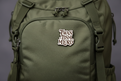 An enamel Pin badge that says TWAS THE TISM, M'LORD. In black writing on a green backpack