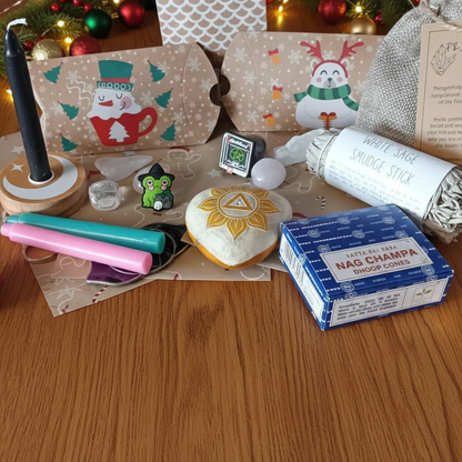 Witchy Advent Calendar with assorted items including a box of Nag Champa incense, crystals, a small figurine, and decorative packaging on a purple surface.
