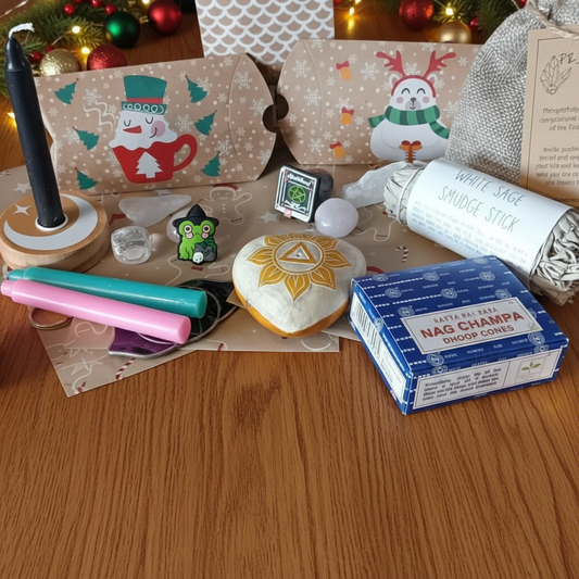 Witchy Advent Calendar with assorted items including a box of Nag Champa incense, crystals, a small figurine, and decorative packaging on a purple surface.
