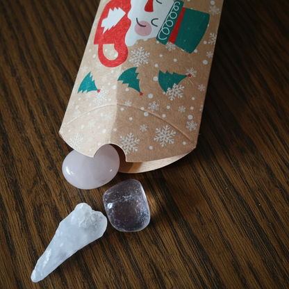 set of three crystals coming from a christmas themed box from a witchy advent calendar on a purple background with bats.
